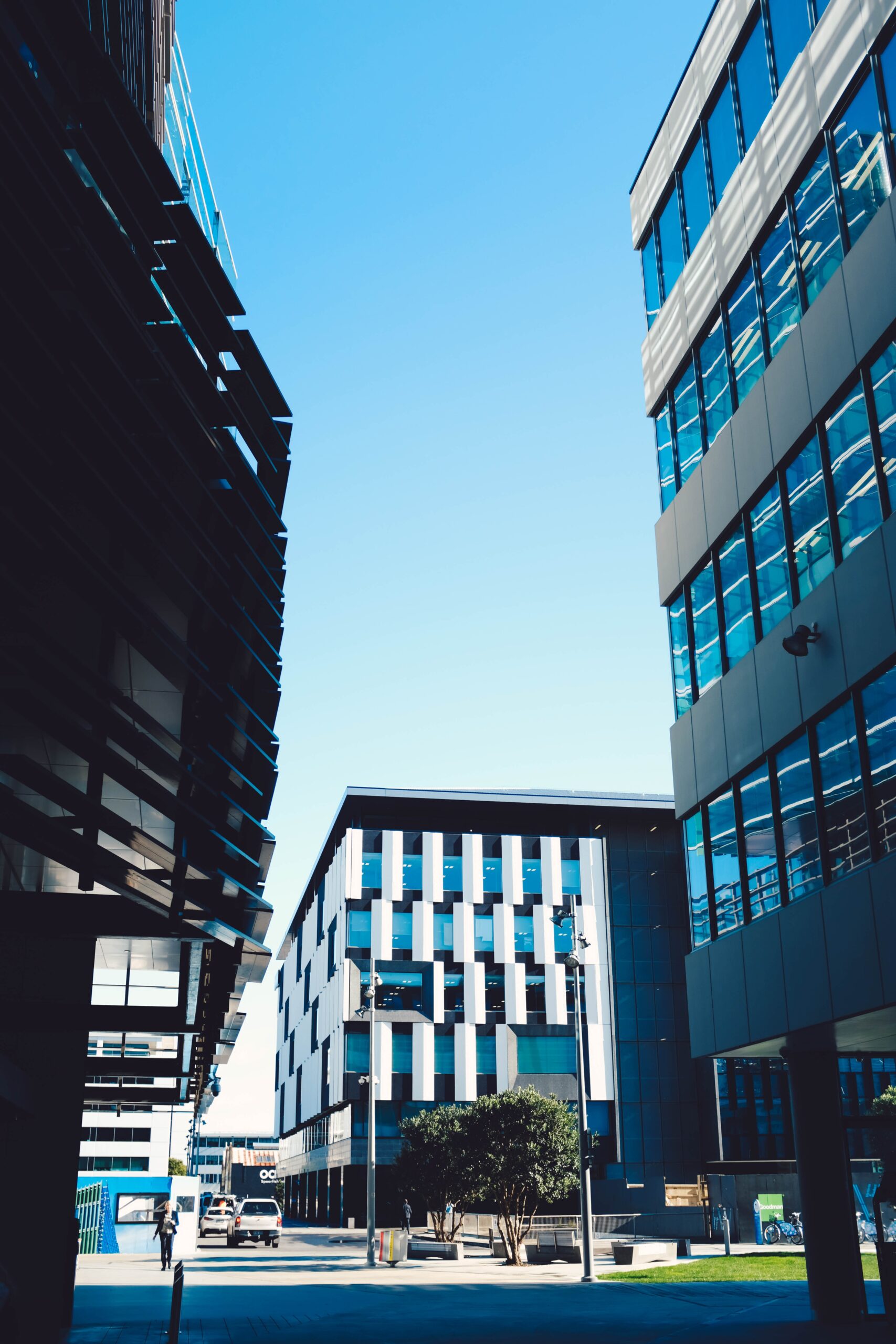 who-we-are Picture Modern Skyscrapers With Blue Windows Parking Area Blue Sky Scaled